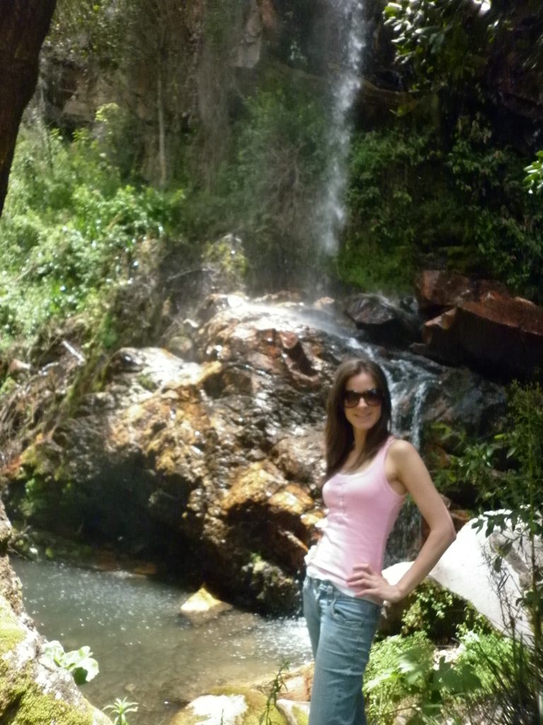 Anna striking a pose next to a waterfall on the trail to the scenic outlook
